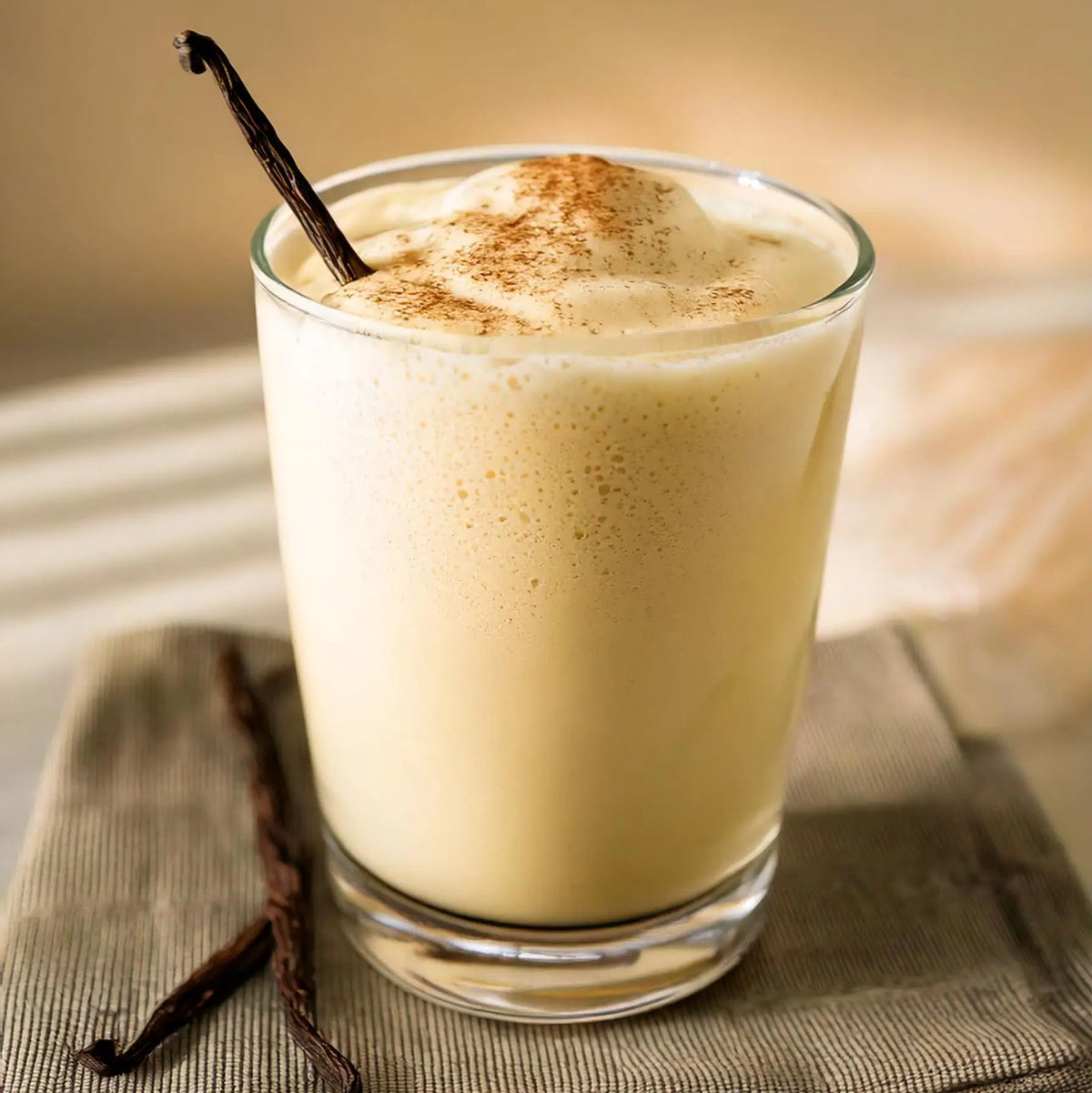 A glass of creamy vanilla protein shake with a vanilla pod