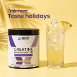 Zelthy creatine with electrolytes and CoQ10 next to an iced pineapple-flavoured drink