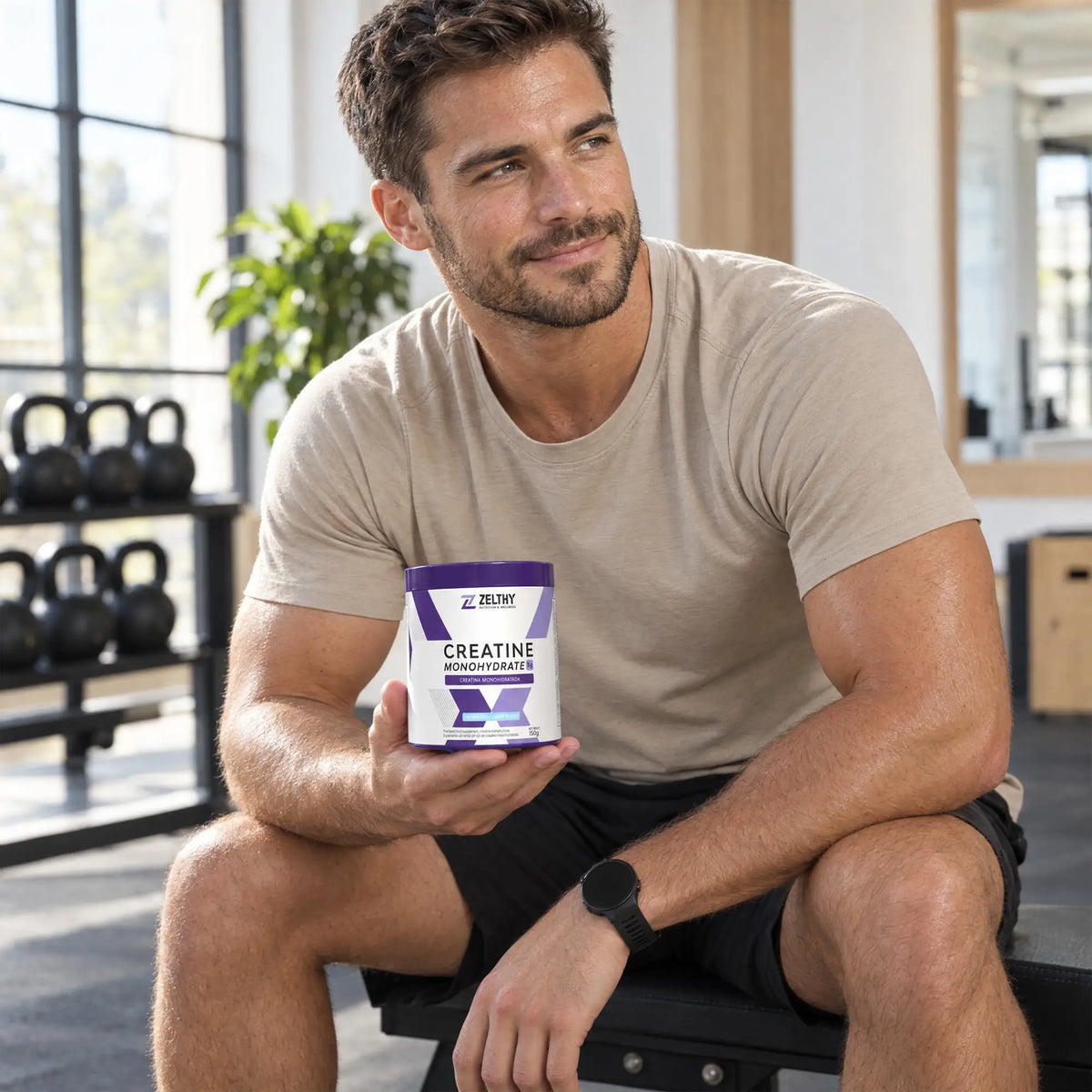 Man holding a Zelthy creatine monohydrate tub in a bright training studio